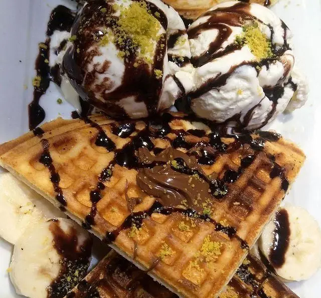 وافل خوشمزه کافه رستوران لی وان با بستنی وانیلی، سس شکلات، موز و پسته، دسری لذیذ و دلنشین برای مشتریان.