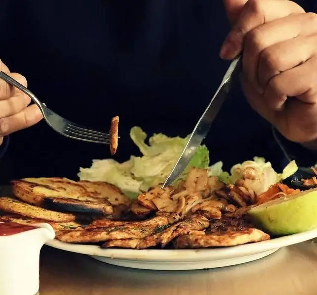 تصویری از مشتری که در حال میل کردن مرغ گریل و سیب زمینی خوشمزه در کافه رستوران لی وان است، با سالادی تازه و سس مخصوص.