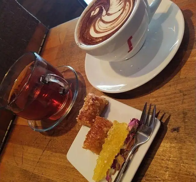 تصویری از میز کافه رستوران لی وان با قهوه هنرمندانه، چای اصیل، باقلوا و نبات زعفرانی. لذت طعم‌های شرقی در لی وان.