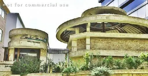 نمای بیرونی جذاب رستوران و کافه گریل گاردن، ساختمانی با معماری مدرن و دایره‌ای شکل، همراه با فضای سبز دلنشین.