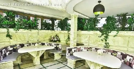 تصویری از فضای باز و زیبای رستوران گریل گاردن، شامل نیمکت‌های سنگی منحنی، میزهای شیک و گل و گیاه سرسبز.