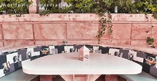 نمایی از فضای باز رستوران گریل گاردن با میز و نیمکت منحنی و دیوارهای آجری صورتی، مکانی دلنشین برای صرف غذا و دورهمی.