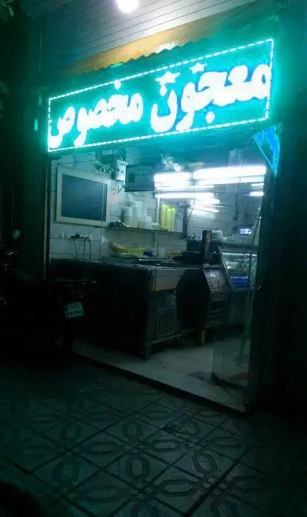 تابلوی نئون سبز "معجون مخصوص" در شب، سردر مغازه بستنی و فالوده حاج ولی با ویترین و کانتر آماده پذیرایی از مشتریان.