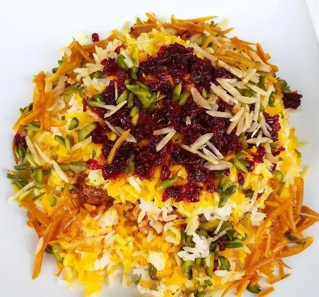 عکس مرصع پلوی مجلسی و خوش رنگ رستوران آجی، تزیین شده با برنج زعفرانی، خلال پسته و بادام، هویج و زرشک. غذای سنتی ایرانی.