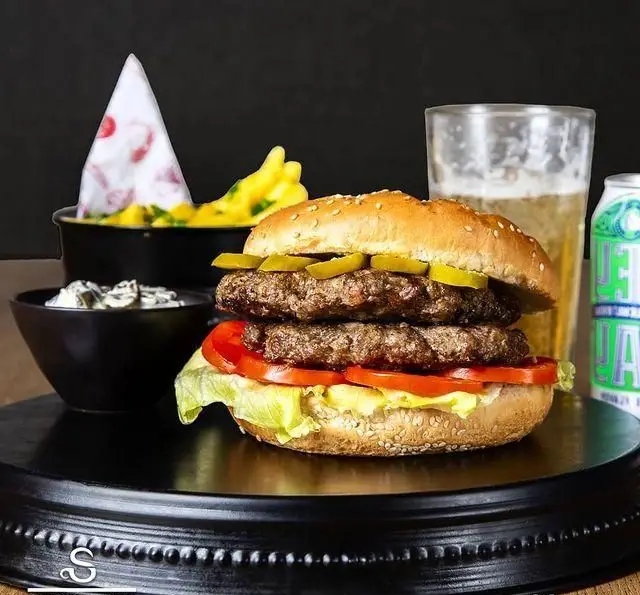 وعده غذایی لذیذ کافه رستوران هفت آسمان: همبرگر دوبل با گوشت تازه، کاهو، گوجه، خیارشور، سیب‌زمینی سرخ‌کرده، سس و نوشیدنی خنک.
