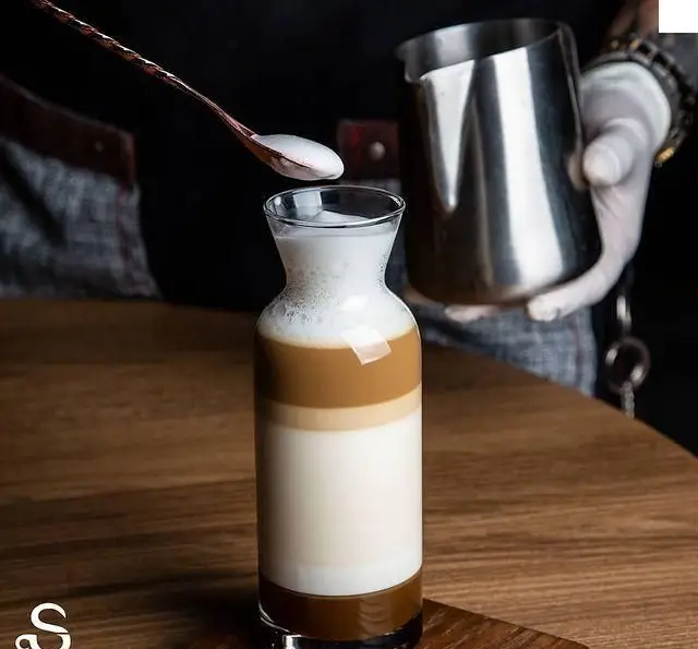 هنر باریستا در آماده‌سازی لاته لایه‌ای و زیبا در کافه رستوران هفت آسمان. نوشیدنی خاص و دلپذیر برای مشتریان ما.