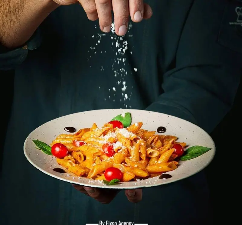 آشپز کافه رستوران هفت آسمان در حال سرو پاستا پنه لذیذ با سس گوجه، گوجه گیلاسی و پنیر پارمزان تازه؛ بهترین غذای ایتالیایی.