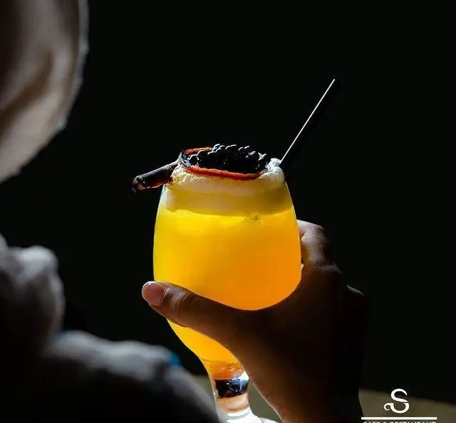 کوکتل استوایی و خنک با پشن فروت در کافه رستوران هفت آسمان، نوشیدنی زرد با تزئین خاص و نی، لحظاتی دلپذیر.