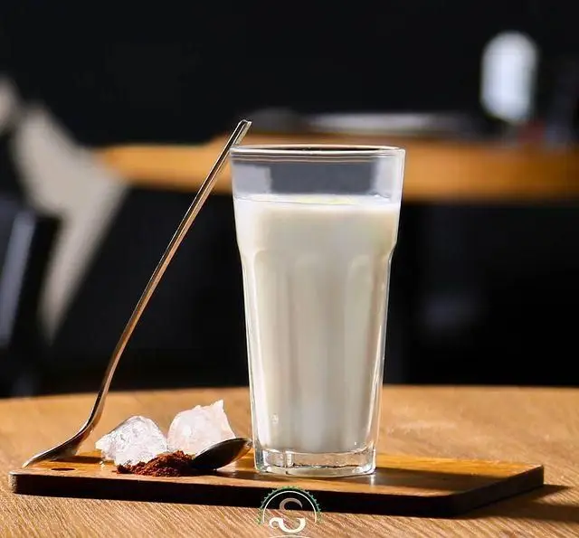 لیوان شیر در کافه رستوران هفت آسمان با قاشق، پودر شکلات و نبات. انتخابی عالی برای شروع روز یا عصرانه.