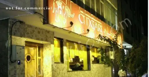 نمای بیرونی رستوران چینگاری در شب، تابلوی نورانی با نام 'CHINGARI' و طرحی سنتی، ورودی چوبی و پنجره‌های روشن محیط گرم آن را نشان می‌دهد.