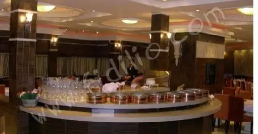 فضای داخلی رستوران نایب با دکوراسیون مدرن و شیک، شامل بوفه مجلل غذا، لیوان‌های کریستالی و میز و صندلی‌های راحت آماده پذیرایی.