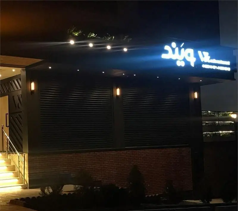 نمای بیرونی کافه رستوران ویند در شب با نورپردازی چشمگیر و تابلوی درخشان. ورودی مدرن و شیک این مکان با پله‌های روشن و فضای جذاب.