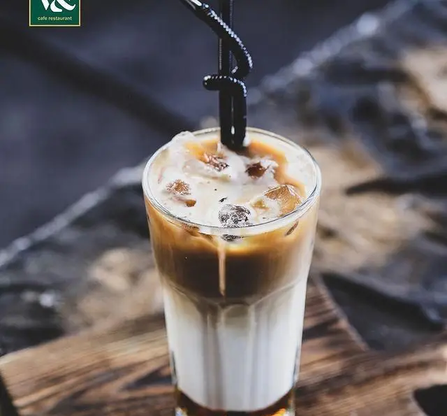 قهوه سرد لاته کافه رستوران ویند: نوشیدنی دلپذیر با لایه‌های شیر و اسپرسو، یخ فراوان و تزئینات زیبا، مناسب هر سلیقه‌ای.