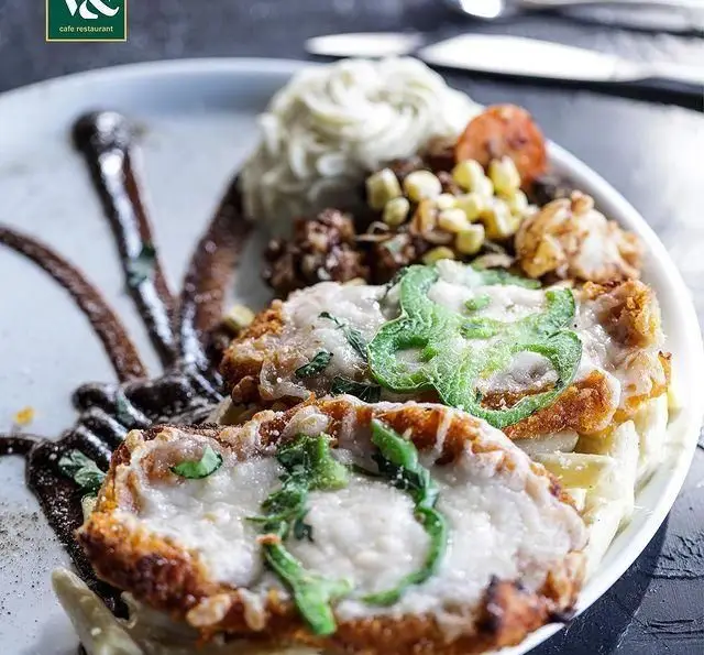 تصویری از یک پرس غذای اصلی لذیذ و دلپذیر کافه رستوران ویند: شنیسل پنیری، پوره، ذرت و گوشت با سس مخصوص.