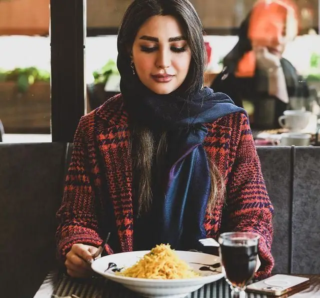 مشتری خانم در کافه رستوران ویند، مشغول لذت بردن از غذای لذیذ در فضایی دنج و دلنشین. تجربه طعم و آرامش در رستوران ویند.