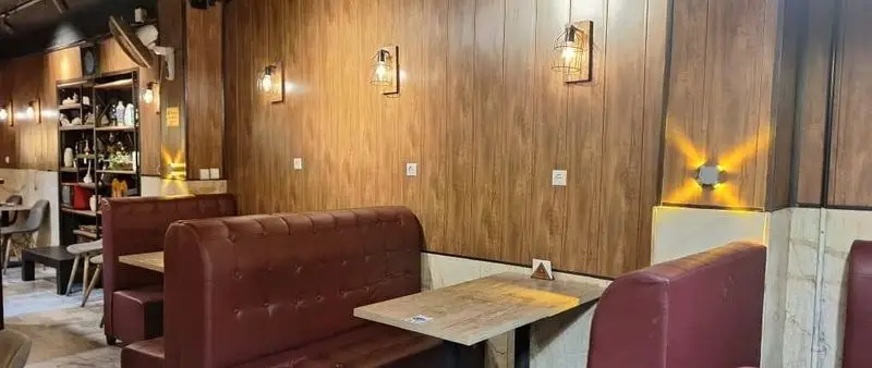 دکوراسیون داخلی کافه آگات با دیوارهای چوبی طرح‌دار، نورپردازی خاص، مبلمان چرمی قرمز و محیطی آرام و دعوت‌کننده.