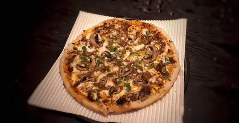 پیتزا مخصوص خوشمزه کافه آگات با ترکیب قارچ تازه، گوشت، زیتون و پیازچه، انتخابی عالی برای تجربه طعم بی‌نظیر و لذت‌بخش.