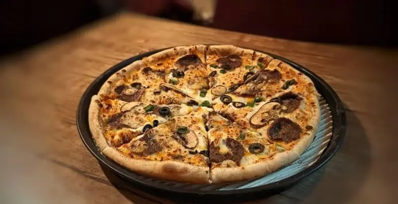 پیتزا قارچ و زیتون مجلسی کافه آگات، تازه پخته شده با خمیر ترد و مواد اولیه باکیفیت، ایده‌آل برای سفارش و تجربه لذیذ در کافه.