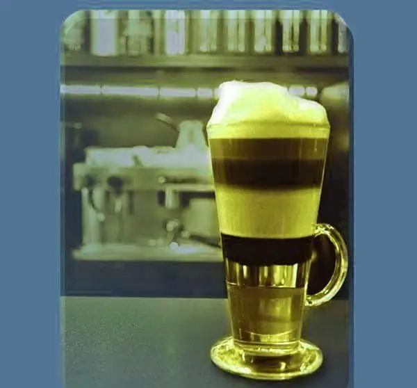 یک نوشیدنی قهوه لایه ای زیبا با فوم غلیظ شیر در لیوان شیشه ای بلند، آماده سرو در کافه میامی برای لذت بخشیدن به شما.