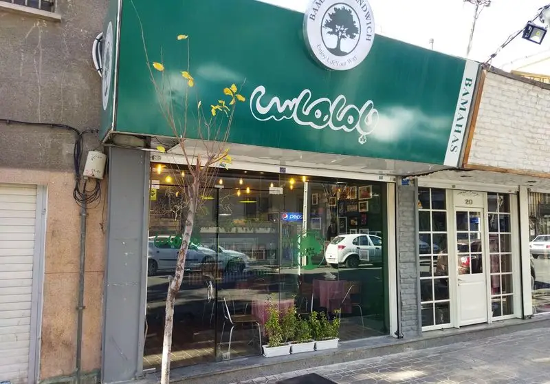 نمای بیرونی رستوران ساندویچ باماهاس با تابلوی سبز روشن و لوگوی درخت. یک فست فود جذاب با ویترین بزرگ شیشه‌ای و محیطی دلباز.