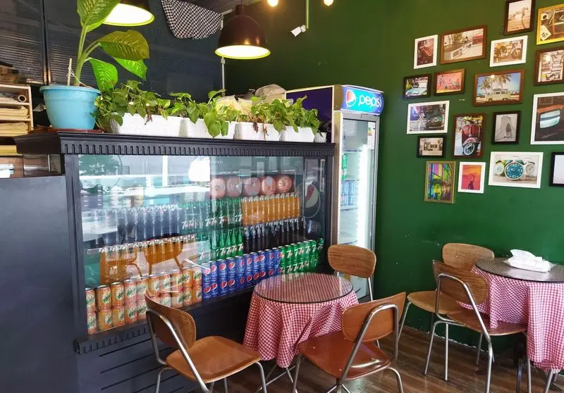 فضای داخلی ساندویچ باماهاس، کافه‌ای دلنشین با یخچال نوشیدنی بزرگ، دیوار سبز رنگ مزین به تابلوها، و میز و صندلی‌های چوبی.