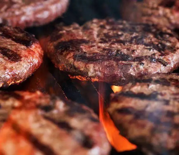 صحنه‌ای دلنشین از همبرگرهای خوش‌طعم و تازه فست فود بام برگر که با شعله‌های آتش گریل، برای شما آماده می‌شوند.