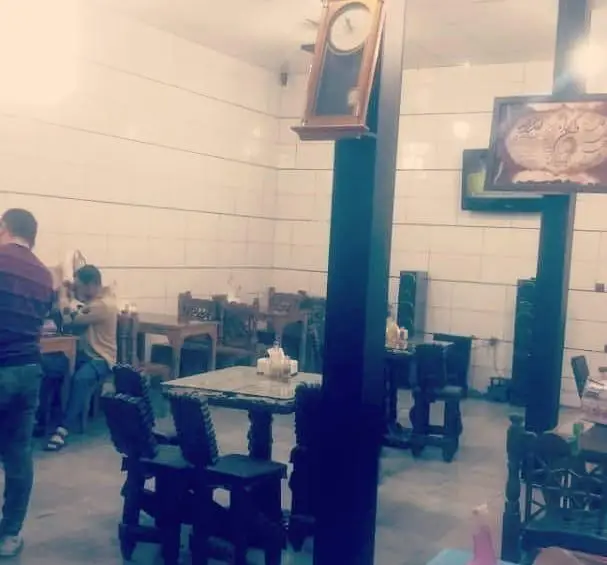 فضای داخلی آرام و دلنشین جگرسرای یاخچی آتا با مشتریان، میز و صندلی‌های چوبی و دیوارهای کاشی‌کاری شده سفید.