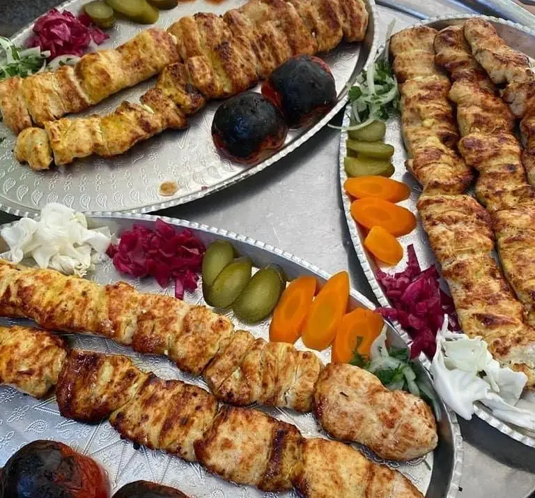 سینی‌های بزرگ کباب مرغ و گوشت کبابی خوشمزه و تازه به همراه گوجه کبابی، ترشی و سبزیجات در رستوران بام شهران.