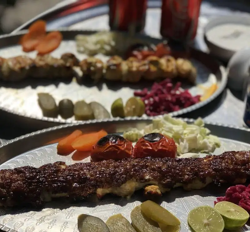 سینی کباب کوبیده و جوجه کباب خوش طعم از منوی رستوران بام شهران، همراه گوجه، ترشی، و مخلفات تازه برای ناهار و شام.