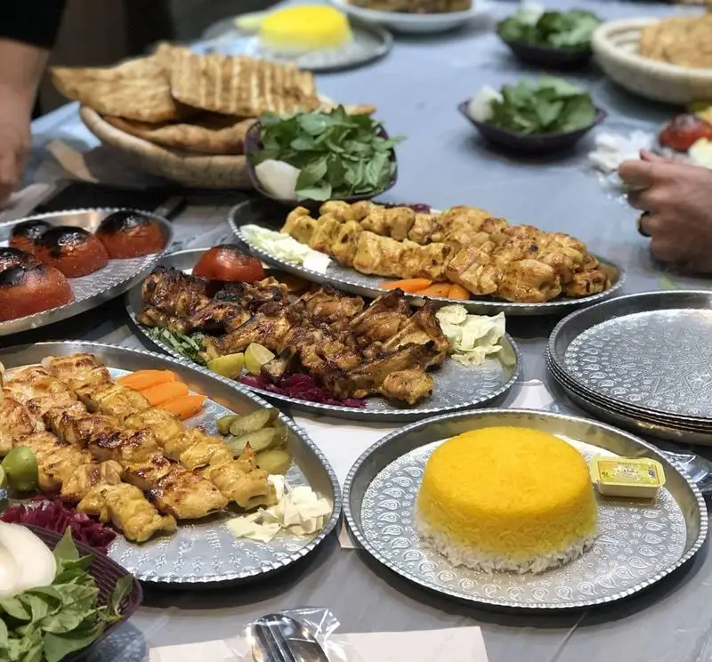 سفره غذای رستوران بام شهران با انواع کباب مرغ، برنج زعفرانی، گوجه کبابی و نان تازه. لذت طعم اصیل ایرانی.