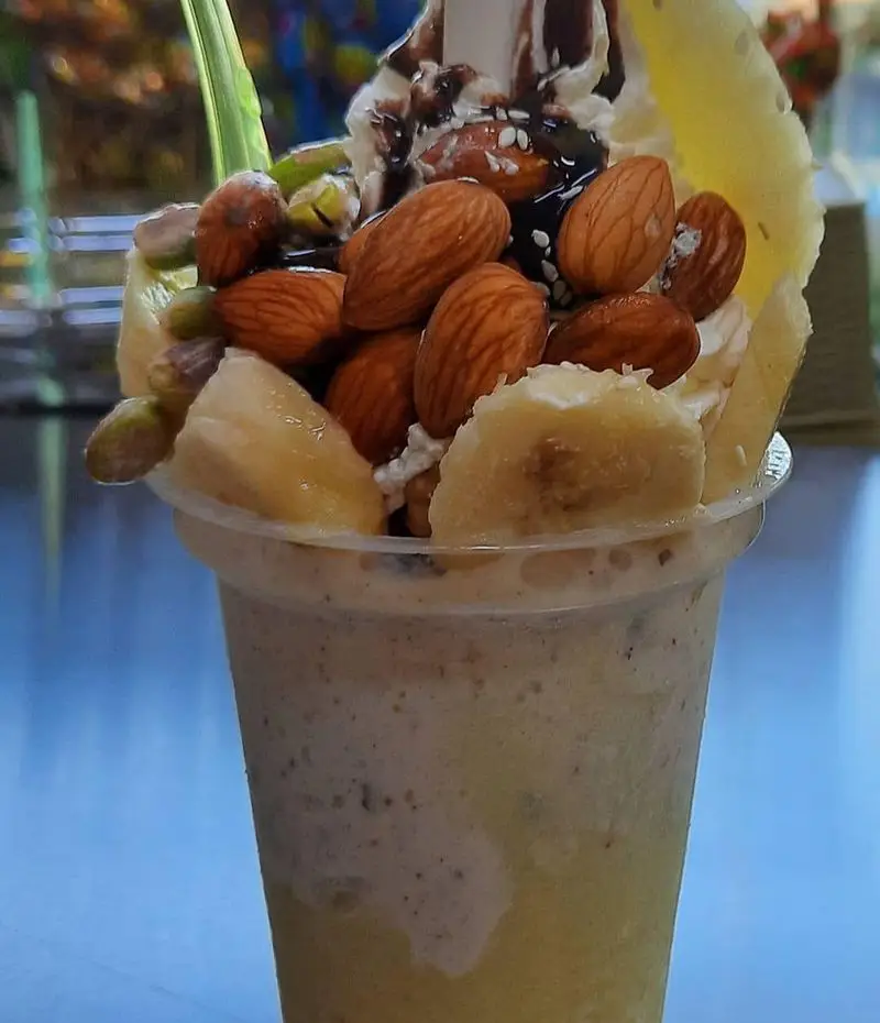 نوشیدنی شیک میوه پرخاصیت آبمیوه بستنی ویتامینه آریا: اسموتی موز، بادام و پسته با خامه و سس شکلات.