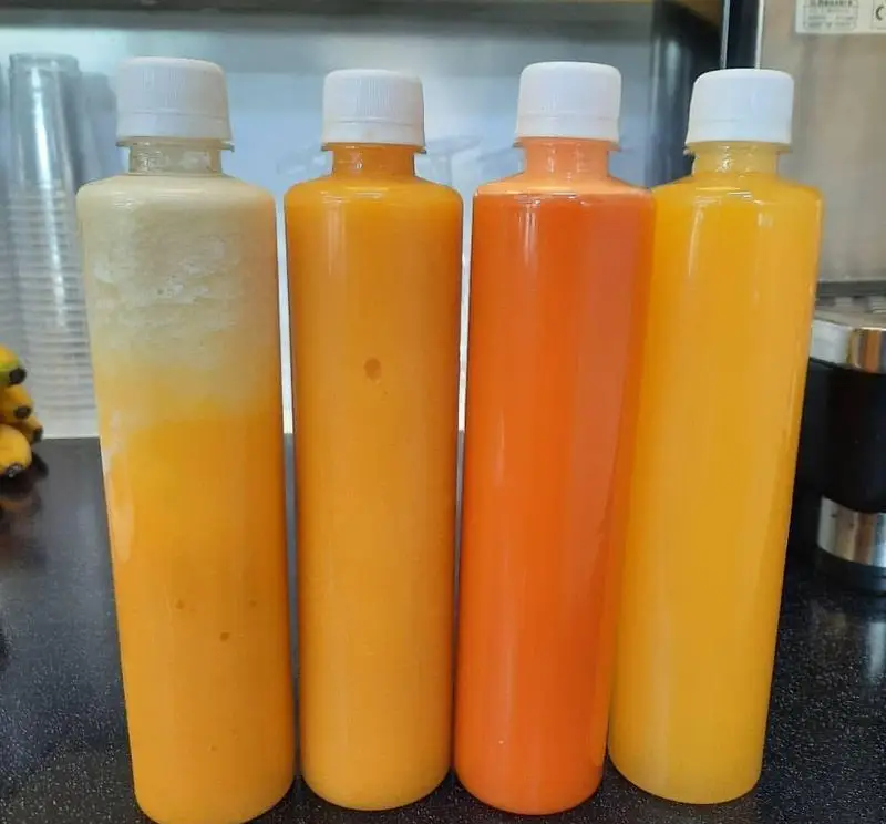 چهار بطری آبمیوه و اسموتی ویتامینه تازه و طبیعی در رنگ‌های شاد زرد و نارنجی، آماده برای مصرف، از آبمیوه بستنی ویتامینه آریا.