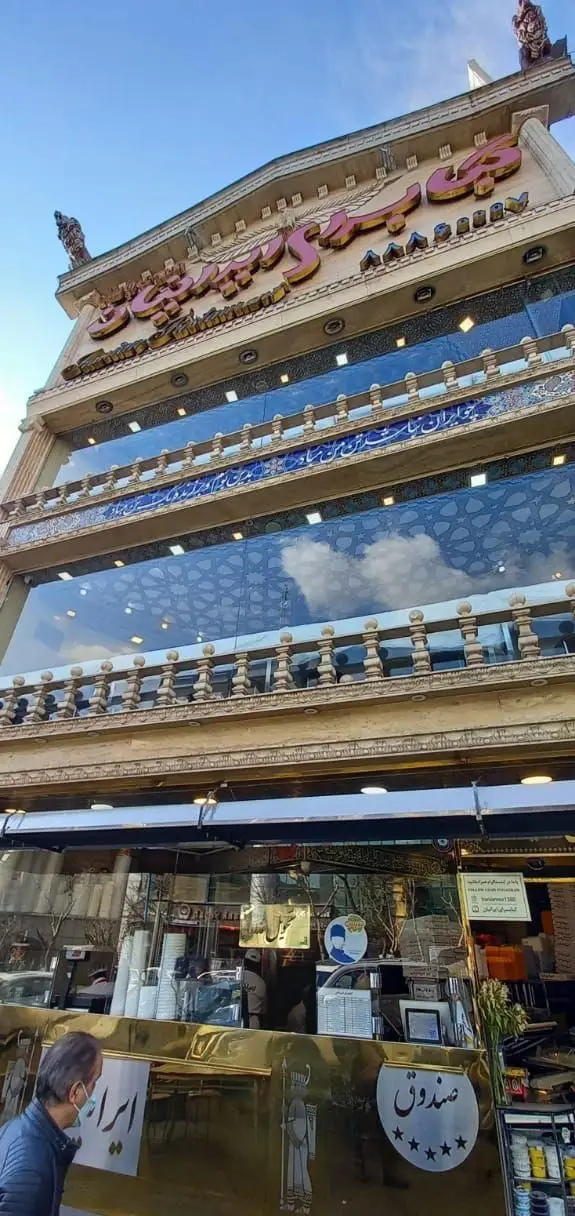 نمای بیرونی و ورودی رستوران ایرانیان، ساختمانی با معماری مجلل و سنتی، تابلوی بزرگ با خط فارسی و کاشیکاری‌های زیبا.