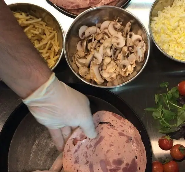 آماده سازی ساندویچ‌های خوشمزه فست فود برگر هال با ژامبون، قارچ و سیب‌زمینی سرخ شده با مواد اولیه تازه و باکیفیت.