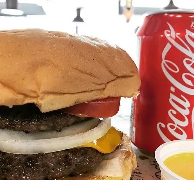 تصویری جذاب از یک برگر دوبل پنیری و آبدار فست فود برگر هال به همراه نوشابه خنک کوکا کولا. بهترین انتخاب برای یک وعده لذیذ.