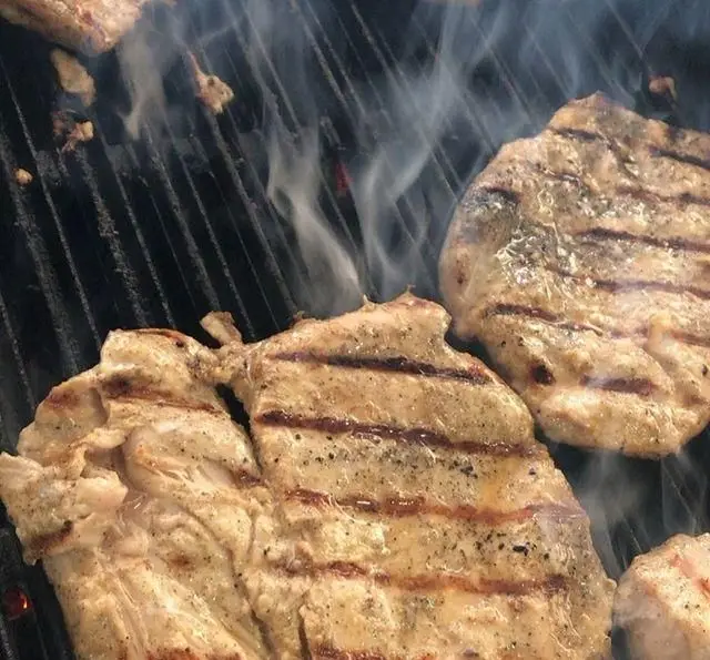 گوشت مرغ یا استیک گریل شده آبدار با خطوط طلایی روی باربیکیو داغ و دودی، آماده برای ساندویچ‌های لذیذ فست فود برگر هال.