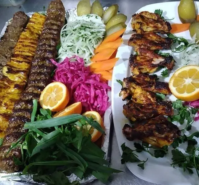انواع کباب ایرانی شامل کوبیده، جوجه کباب و مرغ گریل شده در باغچه رستوران دیپلمات با سبزیجات تازه و دورچین اشتهاآور