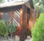 فضای بیرونی دنج و سنتی باغچه رستوران دیپلمات شامل سازه‌ای چوبی با جزئیات هنری و سقف کاهگلی، در دل طبیعت سرسبز.