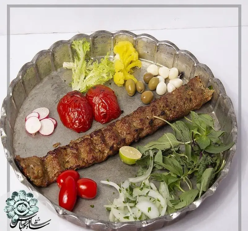غذای اصیل ایرانی: کباب کوبیده رستوران شاطر عباس با گوجه کبابی، تربچه، زیتون، سیر ترشی، پیاز، لیمو و سبزی تازه روی سینی.