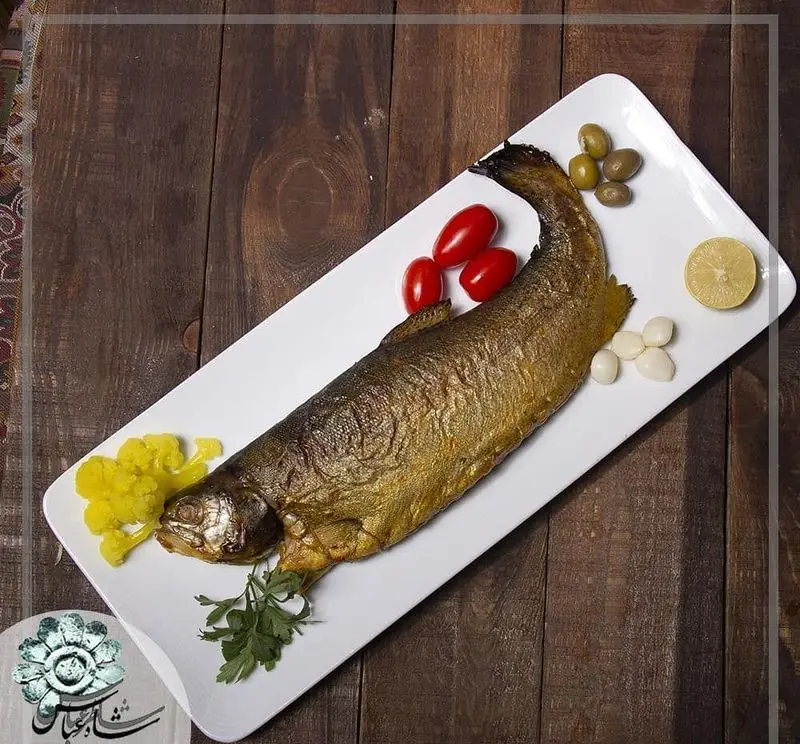 ماهی قزل آلای کامل و لذیذ، غذای دریایی محبوب رستوران شاطر عباس، با چاشنی لیمو، سیر، زیتون و ترشی. انتخابی عالی برای ناهار و شام.