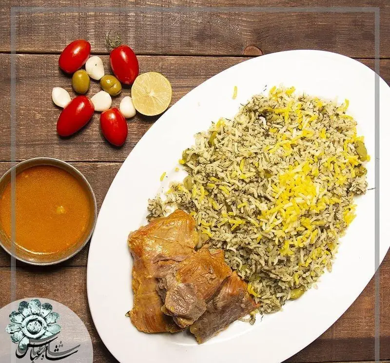باقالی پلو با گوشت گوسفندی، سس مخصوص و مخلفات شامل گوجه، زیتون و سیر در رستوران شاطر عباس. غذای ایرانی.