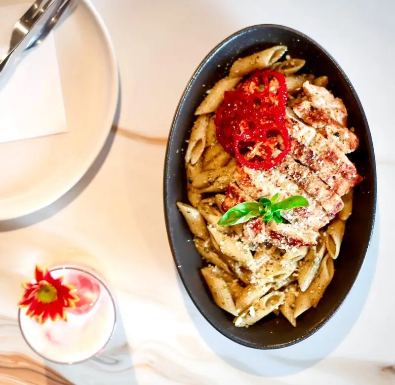 پنه مرغ گریل با سس پستو، گوجه خشک و پنیر از کافه رستوران هوکاچی، یک غذای ایتالیایی لذیذ برای تجربه در تهران.