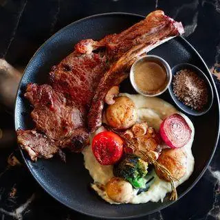 استیک تاماهوک لذیذ با دورچین کامل سیب‌زمینی و سبزیجات در کافه رستوران هوکاجی، انتخابی ایده‌آل برای شام و ناهار.