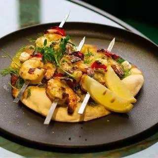 بشقاب میگوهای کبابی آبدار با نان مدیترانه‌ای، لیمو ترش و سبزیجات تازه، آماده سرو در کافه رستوران هوکاجی، یک تجربه غذایی فراموش‌نشدنی.