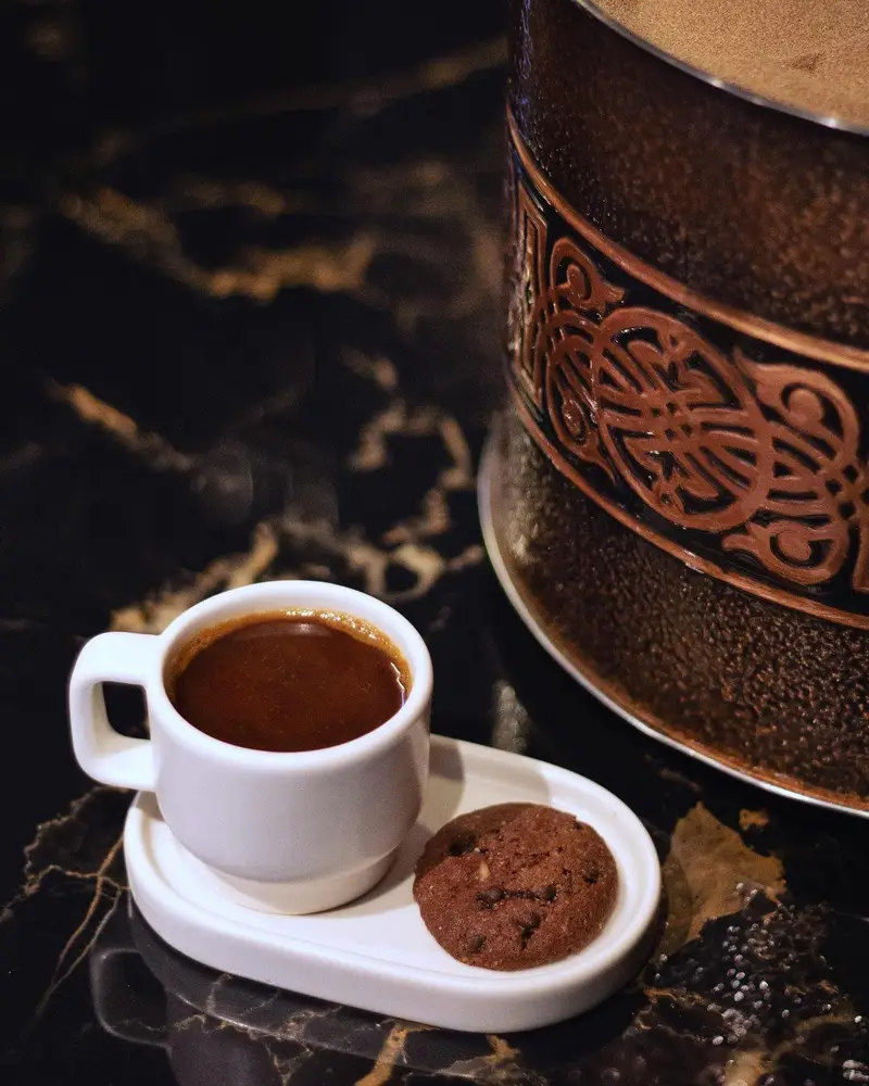 فنجان قهوه ترک و کوکی شکلاتی روی میز مرمری در کافه رستوران هوکاجی. تجربه یک نوشیدنی گرم و دسر دلپذیر در محیطی آرام.