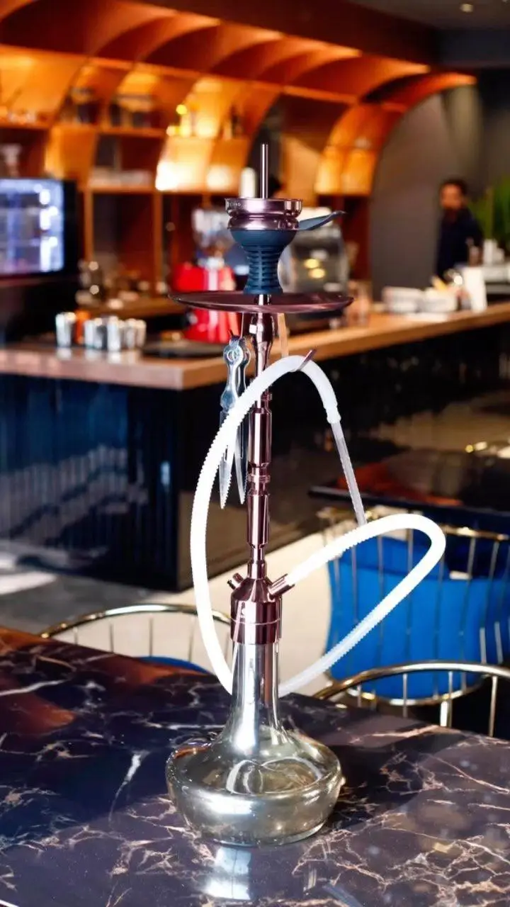 تصویری از یک قلیان مدرن و براق در کافه رستوران هوکاجی، آماده برای سرو روی میز مرمری، نشانگر محیط دلنشین و خدمات با کیفیت.