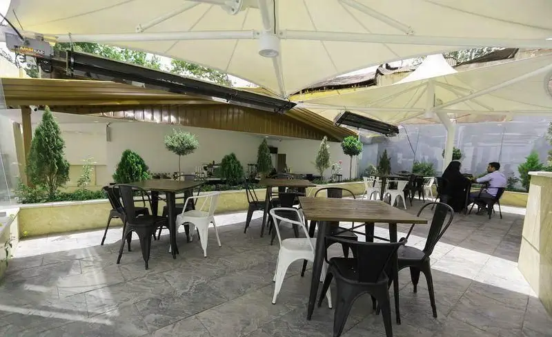 فضای باز رستوران فست فود چیتر چیکن: میز و صندلی‌های شیک، سایبان‌های بزرگ، گرمایش، فضای سبز و دلپذیر برای تجربه غذایی عالی.