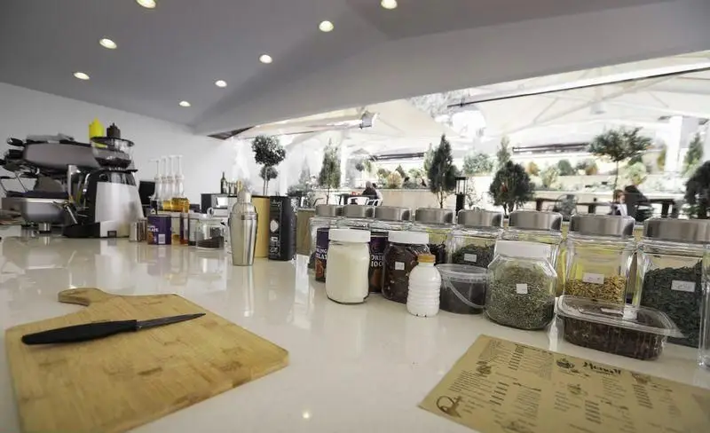 میز سرو نوشیدنی و قهوه در فست فود چیتر چیکن با دستگاه اسپرسو، شیکر و مجموعه‌ای از مواد اولیه و ادویه‌جات معطر.