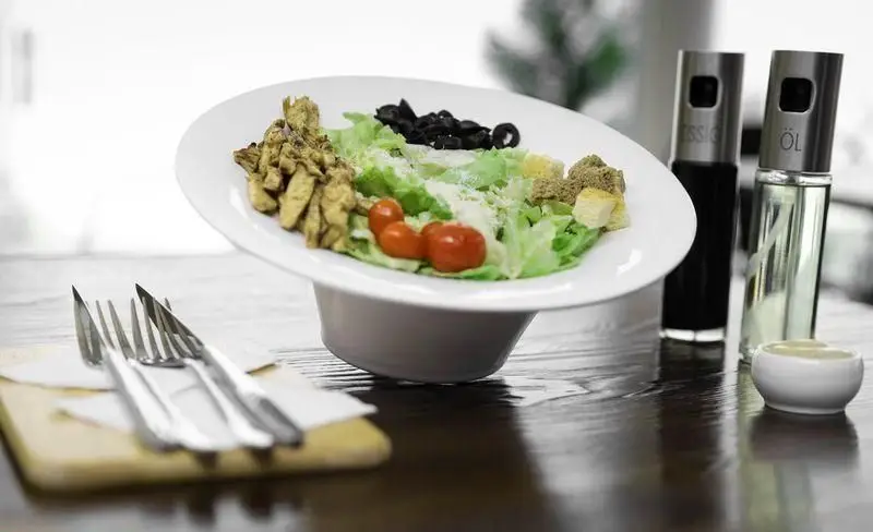 سالاد سزار مرغ تازه و خوشمزه چیتر چیکن با کاهو، زیتون، گوجه و کروتون. انتخابی سالم برای فست فود چیتر چیکن.