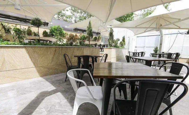 فضای باز جذاب و مدرن فست فود چیتر چیکن، شامل میز و صندلی‌های شیک زیر سایبان‌های بزرگ و محیطی سرسبز و آرامش‌بخش.